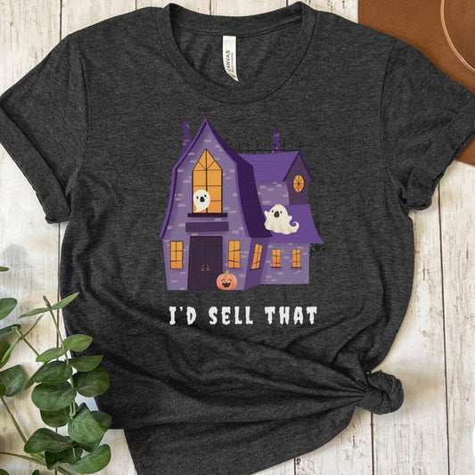 Dark gray heather t-shirt with Halloween-themed graphic and text 'I'd Sell That' on a wooden surface.