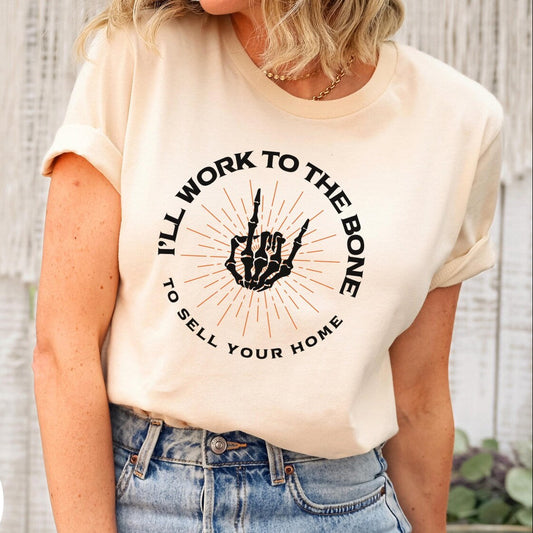 Person wearing a t-shirt with a graphic and text, standing against a wooden wall.
